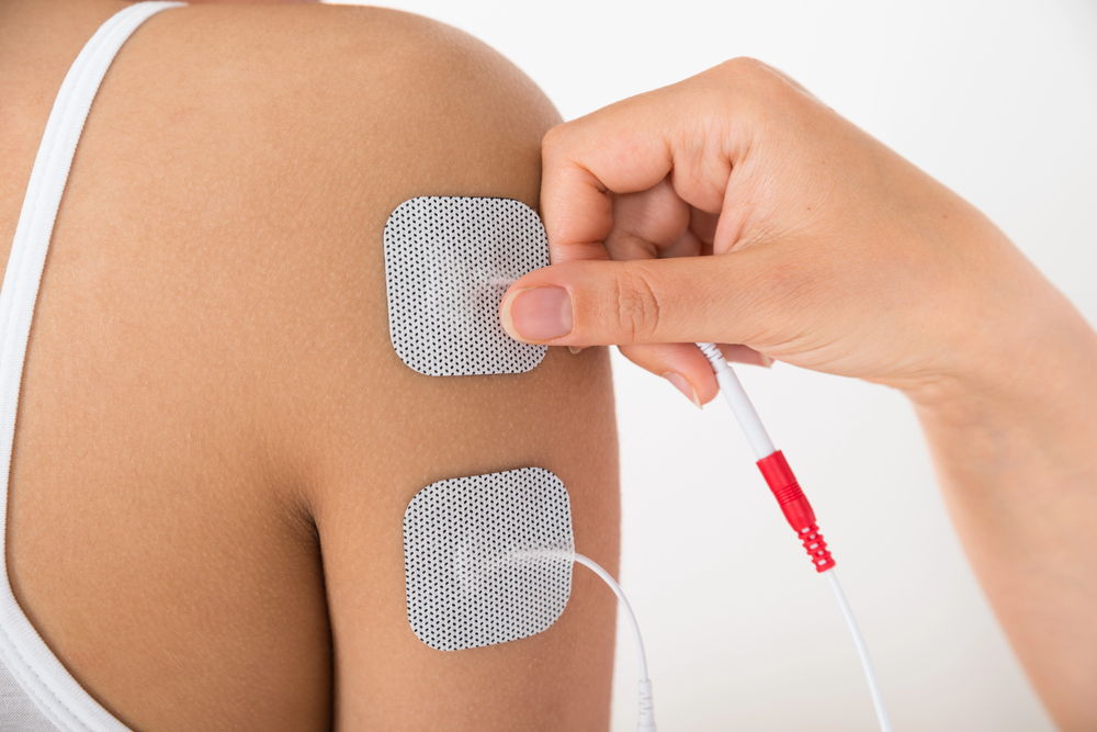A woman receives electrical muscle stimulation therapy for shoulder pain at a roselle chiropractic clinic. 