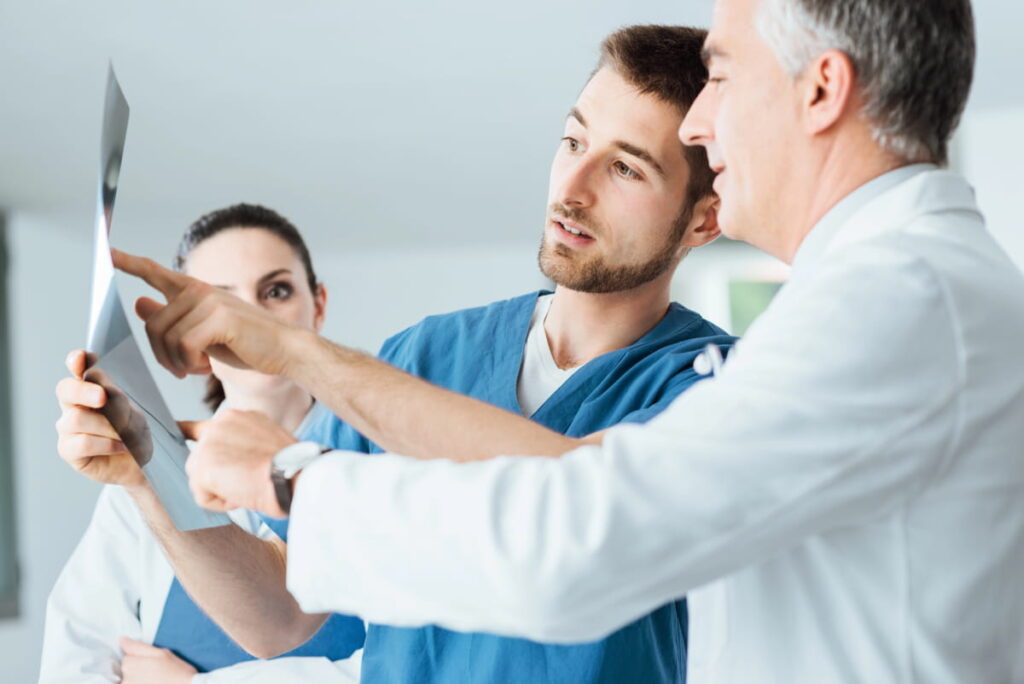 A group of chiropractic professionals examine an x ray from a car crash patient.