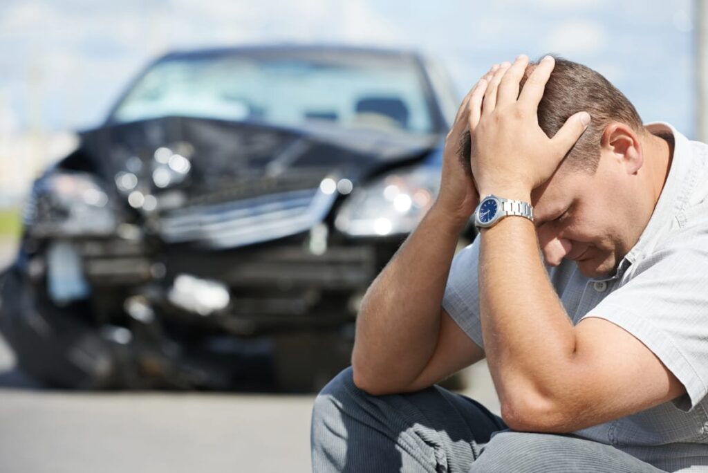 A man holds his head after a car crash.